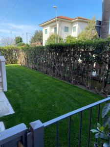 einen Garten mit grünem Gras und einem Zaun in der Unterkunft Appartamento completamente rinnovato, con giardino, a 100 mt dal mare in Marina di Massa