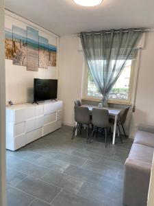 een woonkamer met een eettafel en een televisie bij Appartamento completamente rinnovato, con giardino, a 100 mt dal mare in Marina di Massa