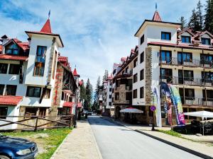 een straat met gebouwen en een auto op de weg bij The Castle Complex in Pamporovo