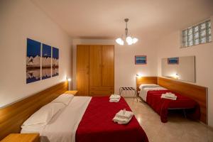 トラーパニにあるSoleTerraLunaのベッドルーム1室(ベッド2台、赤と白のシーツ付)