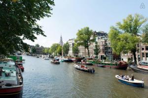 un grupo de barcos flotando por un río con edificios en Canal Dream Apartment, en Ámsterdam