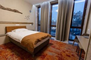 a bedroom with a bed and a desk and windows at HUNNU HOTEL in Ulan-Ude