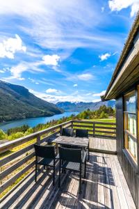 a deck with a table and chairs and a view of a river at Lem Cabins in Sogndal