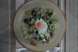 a bowl of soup with an egg and vegetables at Casa de S. Domingos in Évora
