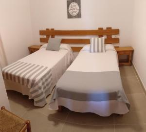 two beds in a room with white sheets at Viviendas Turísticas Vacacionales Allida in Playa Migjorn