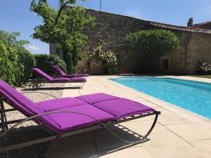 a pair of purple lounge chairs next to a swimming pool at Maison des Bourgades in Saint-Julien-de-Peyrolas