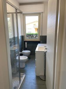 a bathroom with a toilet and a sink and a window at Appartamento completamente rinnovato, con giardino, a 100 mt dal mare in Marina di Massa