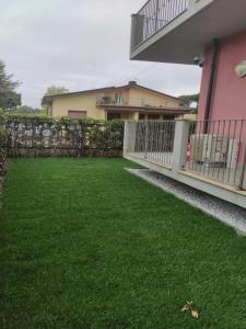 a backyard with a fence and green grass at Appartamento completamente rinnovato, con giardino, a 100 mt dal mare in Marina di Massa