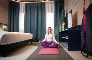 a woman sitting on a rug in a room with a bed at Stay Hotel in Brunello