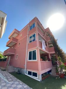 a pink building with the reflection of it at Apartments Nikičić in Bar