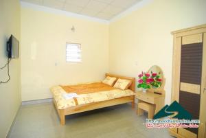 1 dormitorio con 1 cama y un jarrón de flores en Nhà nghỉ Dương Vũ, en Mộc Châu
