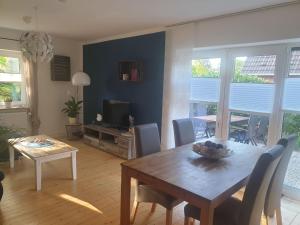 a living room with a wooden table and a television at Kleine Auszeit in Stakendorf +10 photos
