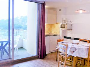 uma cozinha e sala de jantar com uma mesa e uma varanda em Apartment Les Logis du Languedoc by Interhome em Gruissan