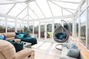 a conservatory with a living room with a glass ceiling at ALTIDO Greenknowes Estate - Retreat With Garden, Parking and Hot Tub in Kelty