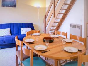 グリュイッサンにあるHoliday Home Les Romarines-6 by Interhomeのダイニングルーム(木製テーブル、青いソファ付)