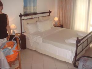a woman standing in a bedroom with a large bed at Alessandro in Sidari