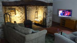 a living room with two couches and a stone fireplace at Blaentwrch Farmhouse in Llanddewi-Brefi