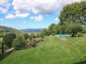 a green yard with a swimming pool and mountains in the background at Holiday Home Lucolena by Interhome in Lucolena in Chianti