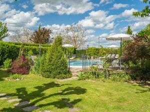 a garden with a swimming pool and umbrella at Holiday Home Casale il Giglio-2 by Interhome in Ciggiano