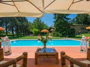 Villa Camporbiano by Interhome في Camporbiano: فناء مع طاولة ومظلات أمام حمام السباحة