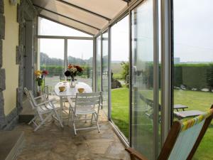 ein Wintergarten mit Glastüren und einem Tisch und Stühlen in der Unterkunft Holiday Home Les Hortensias by Interhome in Kermaria-Sulard