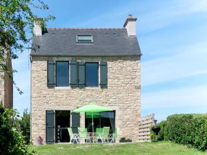 een huis met stoelen en een groene parasol bij Holiday Home Ty Angèle - PLC239 by Interhome in Plouescat
