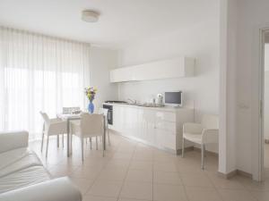 サン・サルヴォにあるApartment Stella Marina by Interhomeの白いキャビネット、テーブルと椅子付きのキッチンが備わります。