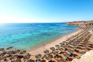 a beach with a bunch of umbrellas and the ocean at Sentido Reef Oasis Aqua Park Resort in Sharm El Sheikh