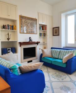 Villa Falconieri Sorrento Suite في سانتّانييلّو: غرفة معيشة مع كنبتين زرقاوين ومدفأة