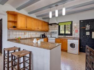 a kitchen with wooden cabinets and a washer and dryer at Holiday Home Forest by Interhome in Benitachell