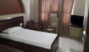 a hotel room with a bed and a television at Wonderful View Hotel WR Bhavnagar in Bhavnagar