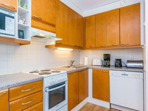eine Küche mit Holzschränken und weißen Geräten in der Unterkunft Holiday Home Karhunvartijan pirtti b2 by Interhome in Ruka + 10 Fotos