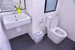 La salle de bains blanche est pourvue d'un lavabo et de toilettes. dans l'établissement บันดารี่ ริชชี่ (Bhundaree Richy), à Hat Yai
