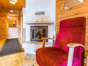 a red chair in a room with a fireplace at Holiday Home Mestarikämpät b10 by Interhome in Ruka