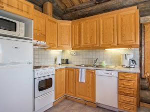 eine Küche mit weißen Geräten und Holzschränken in der Unterkunft Holiday Home Rinnekieppi 1 by Interhome in Ruka