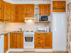 a kitchen with wooden cabinets and a white stove top oven at Holiday Home Karhunvartijan linna c18 by Interhome in Ruka +11 photos