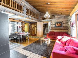 ein Wohnzimmer mit einem roten Sofa und einem Tisch in der Unterkunft Holiday Home Mustalampi 2 kurkiaura by Interhome in Ruka