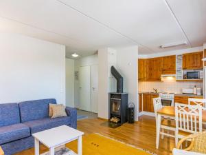 a living room with a blue couch and a kitchen at Holiday Home Karhunvartijan linna c18 by Interhome in Ruka