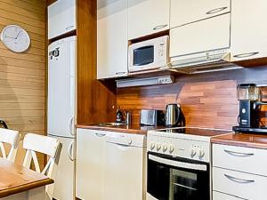 a kitchen with white cabinets and a microwave and a table at Holiday Home Länsirinne c 12 by Interhome in Ruka