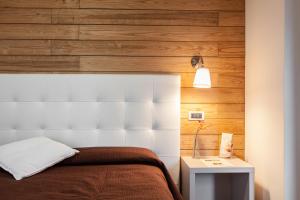 a bedroom with a white headboard and wooden walls at Piccolo Hotel Aurora in Abbadia San Salvatore