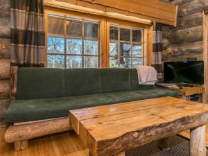 a living room with a green couch and a wooden table at Holiday Home Seitsemän savua 3 by Interhome in Ruka