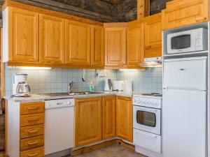 eine Küche mit weißen Geräten und Holzschränken in der Unterkunft Holiday Home Rinnekieppi 2 by Interhome in Ruka + 10 Fotos