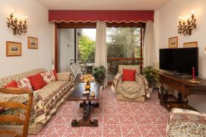 ein Wohnzimmer mit Sofas, einem TV und einem Tisch in der Unterkunft Imperiale Apartment in Forte dei Marmi