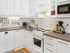 La cuisine est équipée de placards blancs et d'un four avec plaques de cuisson. dans l'établissement Holiday Home Karhunvartijan linna a2 by Interhome, à Ruka