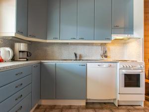 a kitchen with blue cabinets and a white dishwasher at Holiday Home Ruka snow & sun 1 by Interhome in Ruka