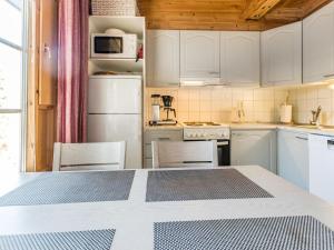 a kitchen with white appliances and a table with chairs at Holiday Home Vuosselinkulma 1 by Interhome in Ruka