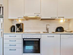 eine Küche mit weißen Schränken, einer Spüle und einem Backofen in der Unterkunft Holiday Home Ruka ski chalets 64- 1210 by Interhome in Ruka