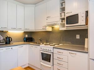 a kitchen with white cabinets and white appliances at Holiday Home Karhunvartijan linna c22 by Interhome in Ruka +12 photos