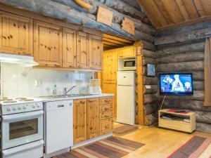 レヴィにあるHoliday Home Atokka by Interhomeの白い家電製品付きのキッチン、ログキャビン内のテレビが備わります。