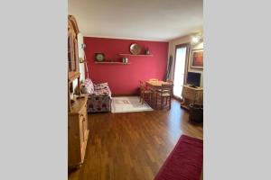 ein Wohnzimmer mit einer roten Wand und einem Tisch in der Unterkunft Appartamento per 5 Abetone, vista Piste. in Abetone